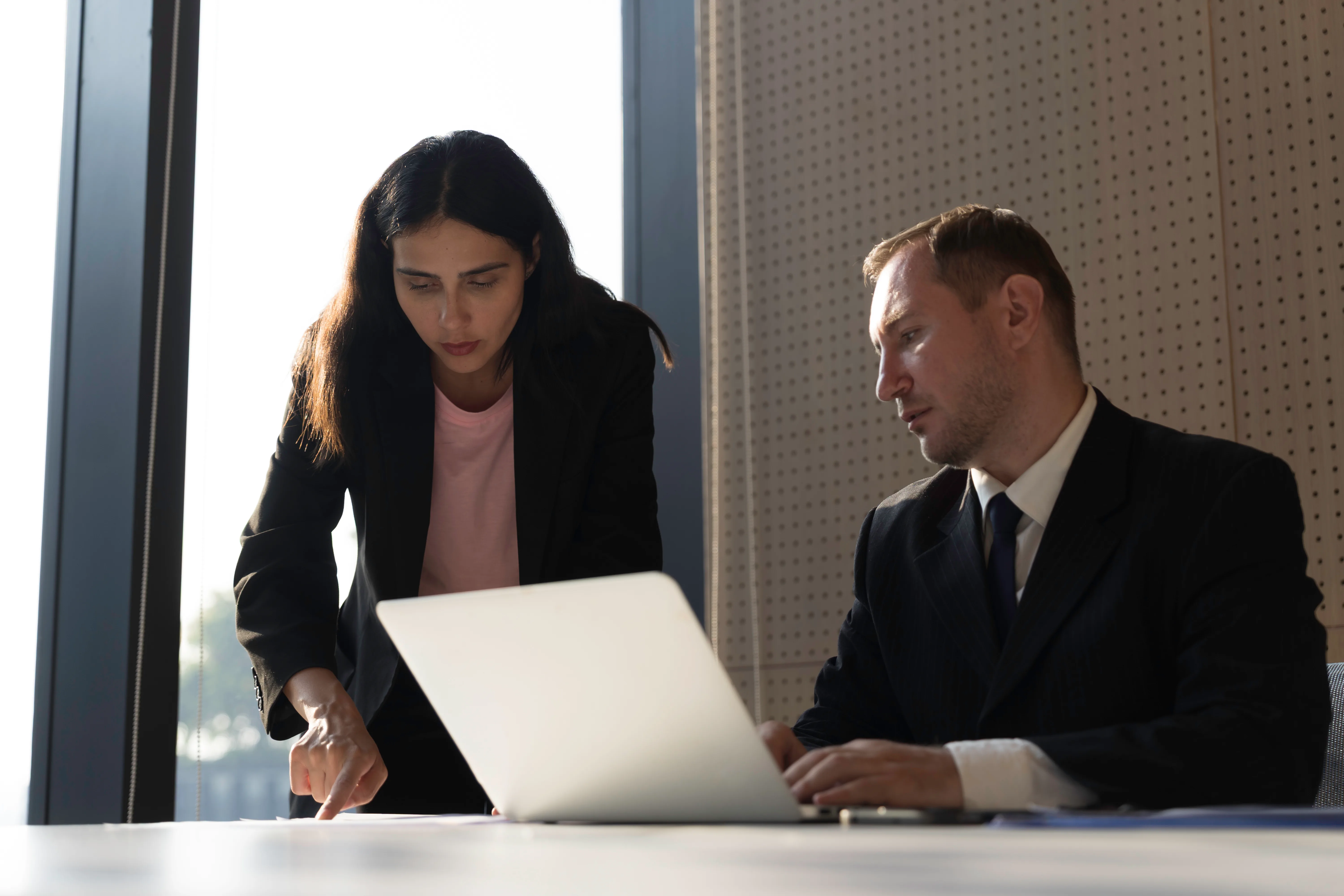 Two business professionals working over a laptop in a meeting room