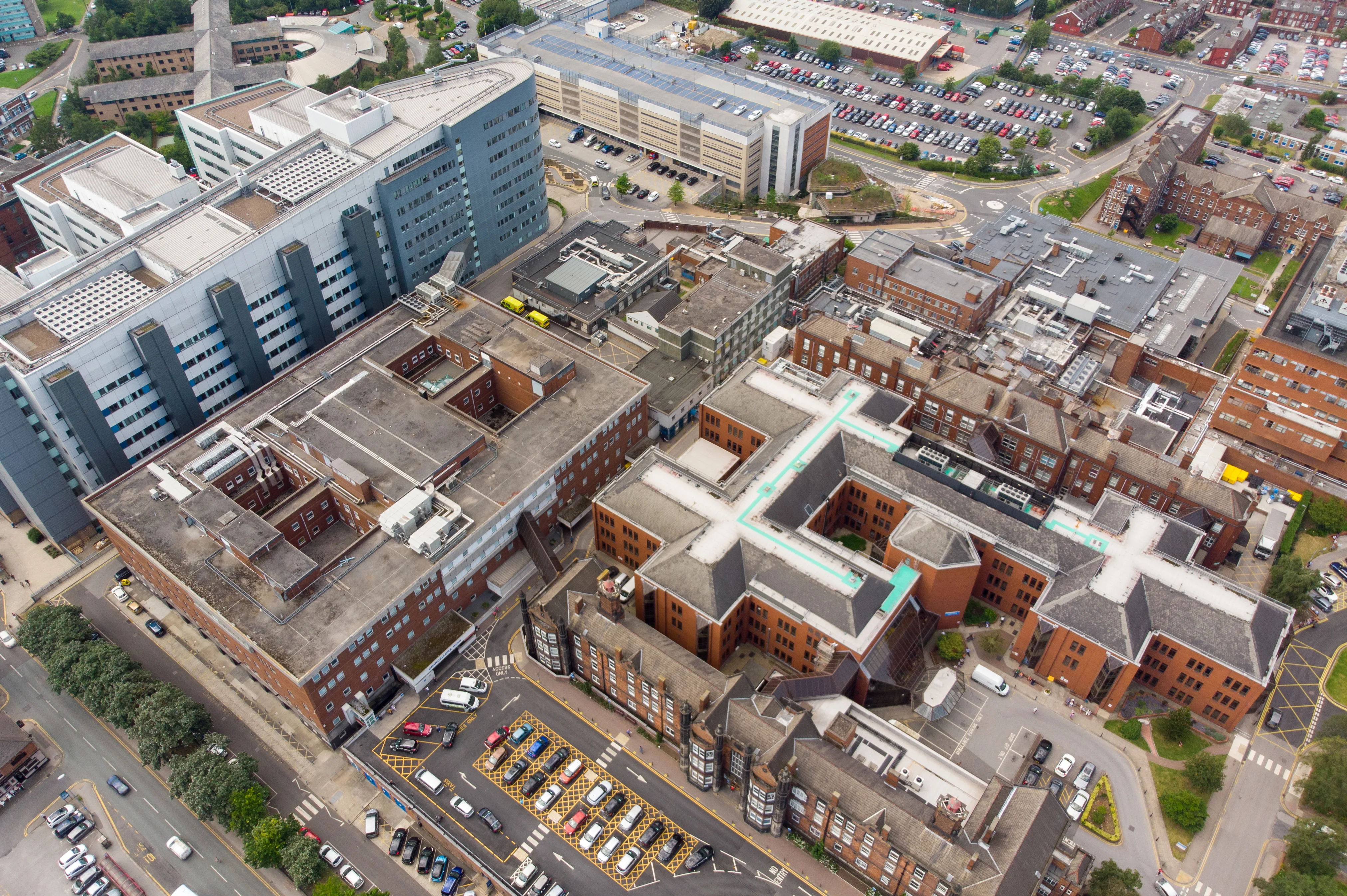 Aerial view of a hospital campus with towers, brick wings, and parking lots